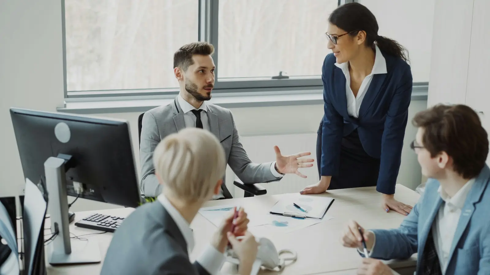 Operations team discussing work around a desk with a monitor